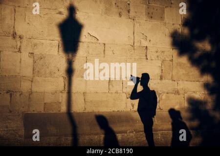 Ombre du photographe sur le mur de pierre. Jeune homme photographiant la vieille rue au coucher du soleil. Zurich, Suisse. Banque D'Images