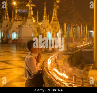 Yangon, Myanmar - 18 décembre 2017 : un homme qui prie à côté de quelques bougies au Shwedagon Pago à Yangon, au Myanmar Banque D'Images