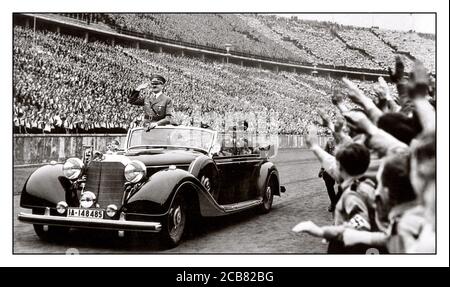 NUREMBERG Adolf Hitler en uniforme portant le brassard de la swastika rend hommage à Heil Hitler aux foules militaires et élancé lors d'un énorme rassemblement nazi en 1938 en Allemagne. Hitler salue les participants à un Reichsparteitag (Reich Party Day) à Nuremberg, en Allemagne. Un Martin Bormann en uniforme est également présent assis à l'arrière de la Mercedes car à toit ouvert Banque D'Images