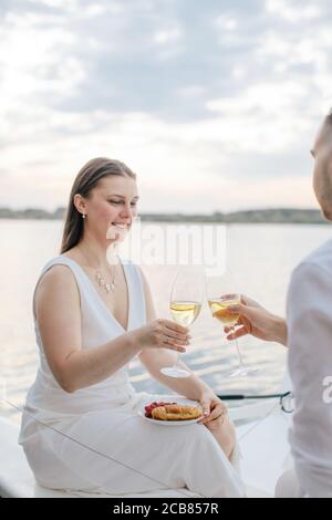 Couple souriant assis sur un yacht avec un verre de vin blanc, Russie Banque D'Images