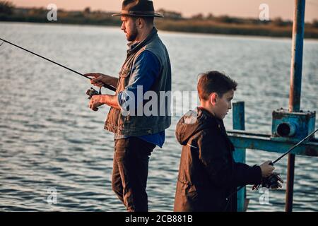 Coucher de soleil. Le père et le fils pêchent sur la jetée Banque D'Images