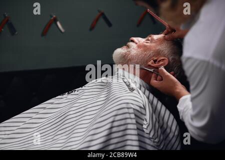 coiffeur créatif tailler la moustache, gros plan sur le côté photo.professional barbiers travaillant sur le saloon. gros plan Banque D'Images