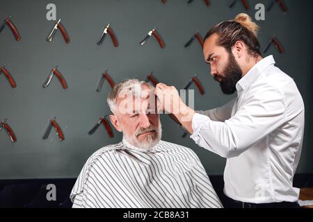 un styliste sérieux et travailleur s'est concentré sur le brossage des cheveux de son client. gros plan Banque D'Images