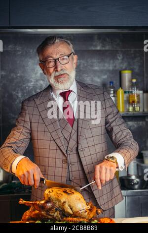 Personnes âgées Housefather respectable habillé de cher mens costume, traite sa grande famille avec fried chicken lors d'un repas de famille Banque D'Images