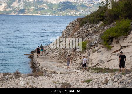 Pusisca, Croatie août 2020 UN groupe d'amis marchant le long de la rive d'une plage cachée dans la forêt, zone devant le bunker abandonné de Yugo Banque D'Images