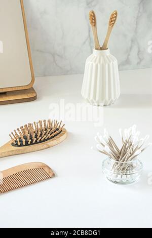 Concept zéro déchet. Ensemble d'accessoires de salle de bain écologiques - brosses à dents en bambou, boutons en coton, brosse à cheveux naturelle, miroir et serviettes en lin. Style de vie durable. Banque D'Images