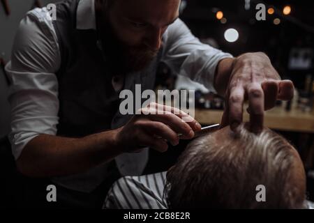 Vieil homme Caucasin de se raser la barbe en hairtician par coiffure rasage au saloon, Close up Banque D'Images