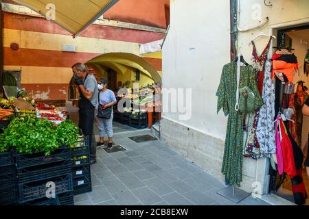 Extérieur d'une épicerie avec des fruits et des légumes exposés dans une ruelle étroite et le épicier avec un masque contre le coronavirus, Ligurie, Italie Banque D'Images