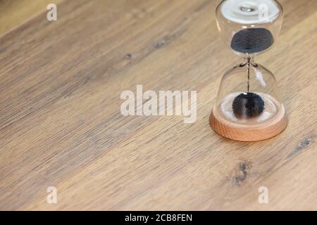 time concept, sablier avec sable noir sur table en bois Banque D'Images