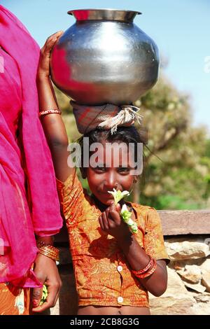 Charmante fille indienne de la famille pauvre avec un pot à eau traditionnel sur la tête. Inde, Rajasthan. fév. 2013 Banque D'Images