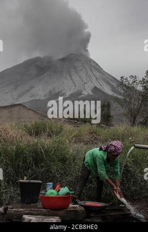 Karo, Sumatra Nord, Indonésie. 12 août 2020. Un villageois nettoie les cendres volcaniques de l'équipement de cuisine du village de Naman Teran un jour après l'éruption du mont Sinabung. La hauteur de la colonne de cendres a été observée à environ 5,000 mètres au-dessus du pic ou à environ 7,460 mètres au-dessus du niveau de la mer. Les récoltes ont échoué en raison de l'épaisse cendre volcanique qui a couvert la zone. Crédit: Albert Ivan Damanik/ZUMA Wire/Alay Live News Banque D'Images