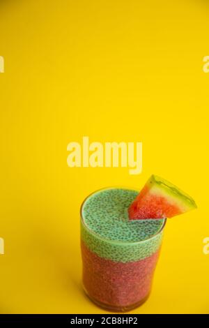Gros plan d'un verre de gâteau de chia noir avec goût de pastèque sur fond jaune Banque D'Images
