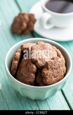 Biscuits sucrés. Biscuits croquants au chocolat forment une fleur dans un bol sur une table en bois vert. Banque D'Images