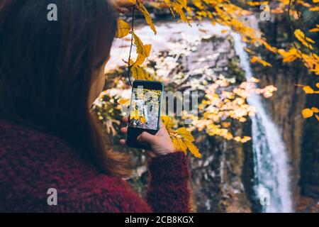 Woman taking photo de chute d'automne sur le téléphone Banque D'Images