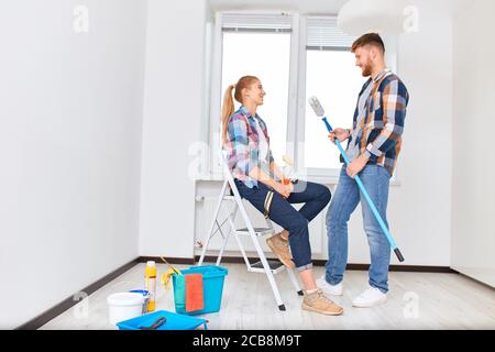 Personnes, rénovation et concept de décoration - jeunes couples de locataires mariés discutant des idées de rénovation et de décoration avant qu'ils commencent à peindre blanc wal Banque D'Images