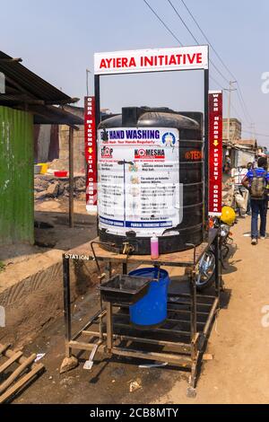 Un grand réservoir d'eau en plastique avec un panneau de lavage des mains gratuit sur lui pour combattre le coronavirus par le côté d'une route de terre, Nairobi, Kenya Banque D'Images