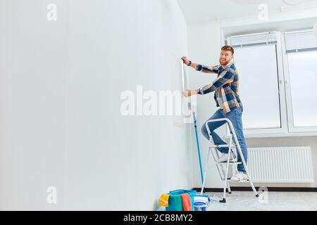 Mur de mesure d'architecte ou d'interio avec règle flexible debout sur une échelle dans un appartement blanc vide Banque D'Images