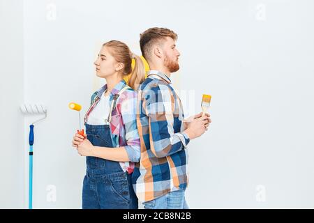 Portrait de jeunes peintres confiants et divers, debout avec des outils de peinture dos à dos, isolés sur fond blanc. Banque D'Images