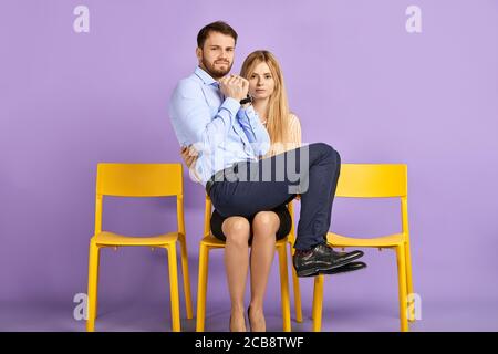 Des élèves amicaux, hommes et femmes, s'amusent et jouent à l'imbécile. Jeune homme assis sur les genoux d'une femme, regardant à la caméra et attendant un entretien d'emploi Banque D'Images