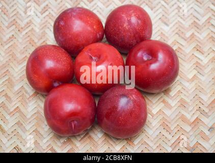 Prune unique isolée sur fond blanc. Gros plan de fruits. Prune rouge bordeaux violet à la cerise Banque D'Images