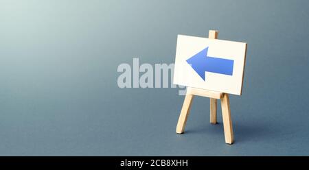 Chevalet avec une flèche bleue vers la gauche. Signe de direction. Publicité de l'emplacement d'un magasin ou d'un point de vente. Minimalisme. Restriction de mouvement, changement de cour Banque D'Images