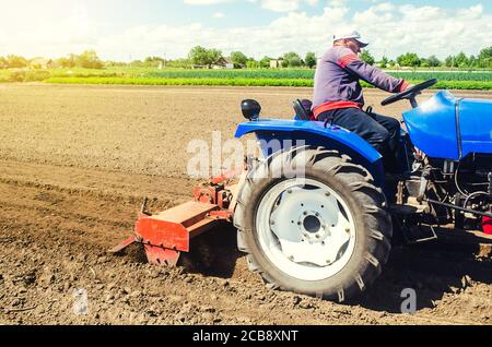 Un agriculteur sur un tracteur travaille le champ avec une déchiqueteuse pour préparer la plantation d'une nouvelle récolte. Desserre, meule et mélange le sol. Surface de desserrage du versoir Banque D'Images