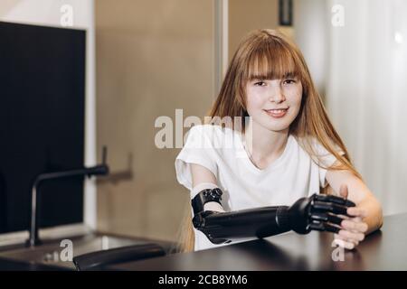 une fille souriante, avec un bras artificiel, regardant l'appareil photo à l'intérieur. gros plan, espace de copie Banque D'Images