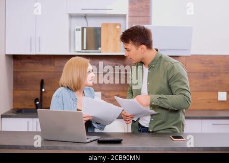 la jeune famille caucasienne était composée d'hommes et de femmes qui débattaient des problèmes financiers de la famille, discutaient et calculaient les dépenses Banque D'Images
