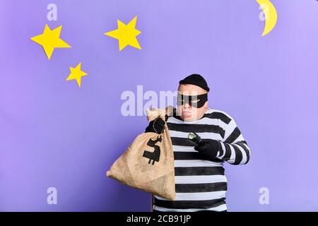 prisonnier prudent avec un sac essayant de se cacher de la police. portrait en gros plan. arrière-plan bleu isolé. studio shot Banque D'Images