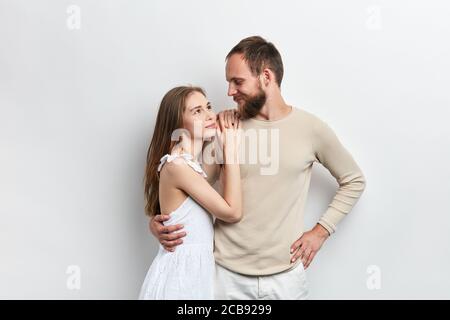 fille avec de longs cheveux bruns mettant ses bras sur l'épaule de son gars, s'appuie sur lui, relation entre la femme et le mari , isolé arrière-plan blanc Banque D'Images