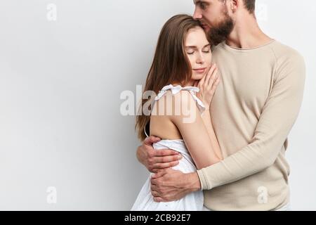 l'homme embrasse sa femme, en tenant dans la hug serré, gros plan rogné phdoto. tendre sensation et émotion . espace de copie, isolé arrière-plan blanc Banque D'Images