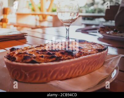 Le lasagne bolognese est servi dans un restaurant dans un bol traditionnel en céramique avec un verre de vin. Restaurant sur la côte de la mer adriatique Banque D'Images