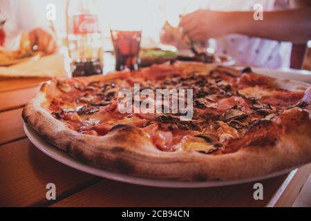 Gros plan sur une délicieuse pizza au jambon aux champignons servie dans un restaurant sur la mer méditaranée Banque D'Images