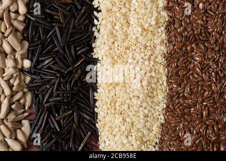 Différentes céréales et graines - maïs, courge, café, quinoa, poivre, riz, millet de tournesol - sur une surface brune Banque D'Images