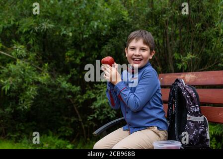 Petit garçon avec sac à dos manger de la pomme fraîche sur un rue Banque D'Images