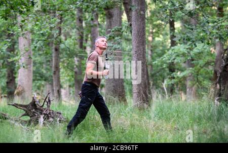 28 juillet 2020, Hessen, Mörfelden: Markus Dietz, biologiste, marche à travers la forêt avec une antenne de suivi. Certaines chauves-souris de la colonie portent des émetteurs. Depuis environ 20 ans, des biologistes étudient régulièrement le développement de la population de chauves-souris dans une zone forestière près de Mörfelden-Walldorf. (Zu dpa série d'été 'Night SHIFTt' 'Bat chercheur: Travailler la nuit dans la forêt enrichit l'environnement vivant' par Andrea Löbbecke) photo: Andreas Arnold/dpa Banque D'Images