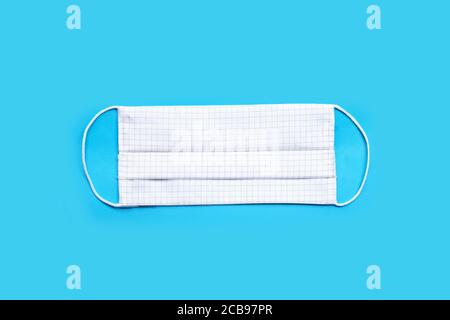 Masque en tissu blanc fait main sur fond bleu. Vue de dessus Banque D'Images