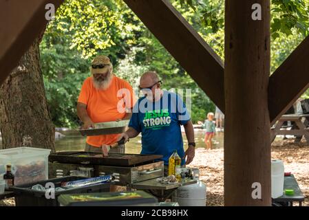 Des hommes grillent des hamburgers le long de la rivière Chattahoochee à Helen, en Géorgie, pour une réunion de famille à la fin d'une série de tubing sur la rivière. (ÉTATS-UNIS) Banque D'Images