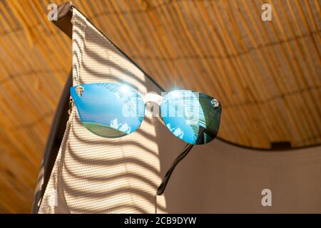 Des lunettes de soleil avec lentille bleue reflètent le soleil. Modèle œil de chat pour femme en gros plan. Mise au point sélective Banque D'Images