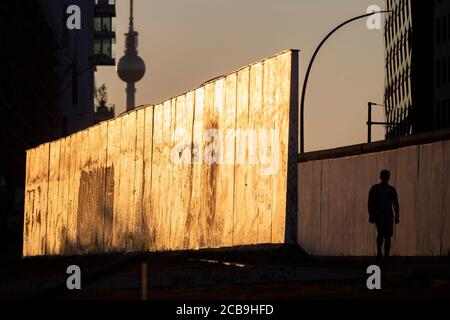 Berlin, Allemagne. 11 août 2020. Un homme marche à l'East Side Gallery dans la lumière du soir entre deux morceaux du mur de Berlin. Il y a 59 ans, le 13 août 1961, commença la construction du mur, qui divisa Berlin pendant plus de 28 ans. Credit: Christoph Soeder/dpa/Alay Live News Banque D'Images