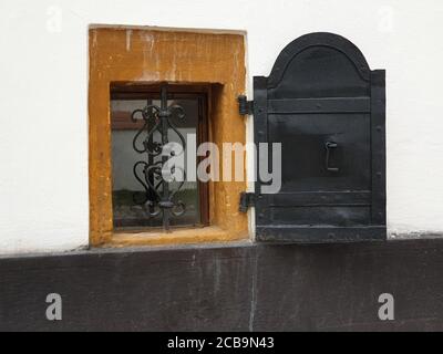 Ouverture du petit volet métallique de la fenêtre du sous-sol. Détail de l'architecture de la maison fenêtre dans le village de Rimetea, Torocko, comté d'Alba, Roumanie Banque D'Images