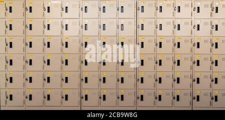 Casier en gros plan beige avec serrure et étiquettes jaunes numérotées dans le vestiaire. Casier pour le stockage de sécurité. Rangée de casiers avec porte verrouillée Banque D'Images