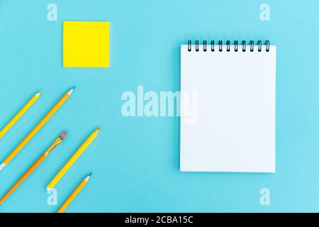 Ouvrez un bloc-notes vierge sur la spirale et les fournitures de bureau et scolaires sur fond bleu. Espace de copie, plan de travail. Concept de retour à l'école. Banque D'Images