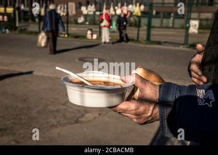 Faites la queue au bus thermique du Malteser Hilfsdienst, où une soupe chaude avec du pain est distribuée quotidiennement devant l'« U » à Dortmund aux personnes dans le besoin et aux sans-abri. Des sacs remplis de nourriture et de vêtements sont également suspendus sur la clôture comme aide d'urgence en temps de crise de Corona. La plupart des établissements de soins pour les sans-abri sont très limités. Par conséquent, l'aide volontaire des citoyens est très importante. Banque D'Images