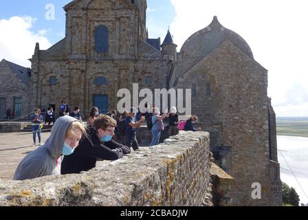 Mont St Michel, France: Juillet 2020: Touristes et visiteurs au Mont St Michel portant des masques tout en regardant la vue Banque D'Images