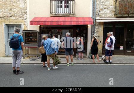 Monpazier, France juillet 2020 : clients qui font des rechapage à l'extérieur d'un boucherie dans une ville française, le nombre de personnes se trouvant à l'intérieur du magasin est limité en raison des restrictions imposées par le coronavirus Banque D'Images