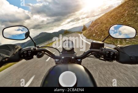 POV de motorbiker maintenant le bar, équitation dans Alpes en beau coucher du soleil Ciel dramatique. Et la liberté de déplacement, activités en plein air Banque D'Images