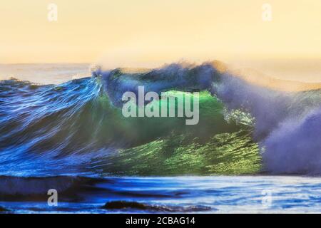 Forte vague se formant comme une grotte au large de la plage de Bronte, dans la banlieue est de Sydney, au lever du soleil dans une douce lumière du matin. Banque D'Images