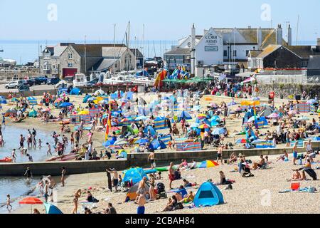 Lyme Regis, Dorset, Royaume-Uni. 12 août 2020. Météo Royaume-Uni. Les vacanciers et les baigneurs de soleil affluent à la plage qui est en train de s'occuper à la station balnéaire de Lyme Regis à Dorset sur une autre journée chaude brûlante et ensoleillée que la vague de chaleur continue. Crédit photo : Graham Hunt/Alamy Live News Banque D'Images