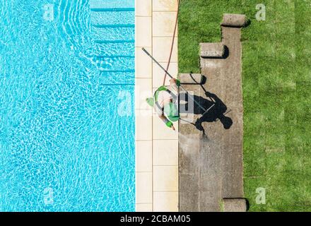 Jardinier caucasien professionnel dans sa pelouse de finition 40s autour de la piscine d'installation de nouvelles tourfs d'herbe. Thème de l'industrie de l'aménagement paysager. Banque D'Images